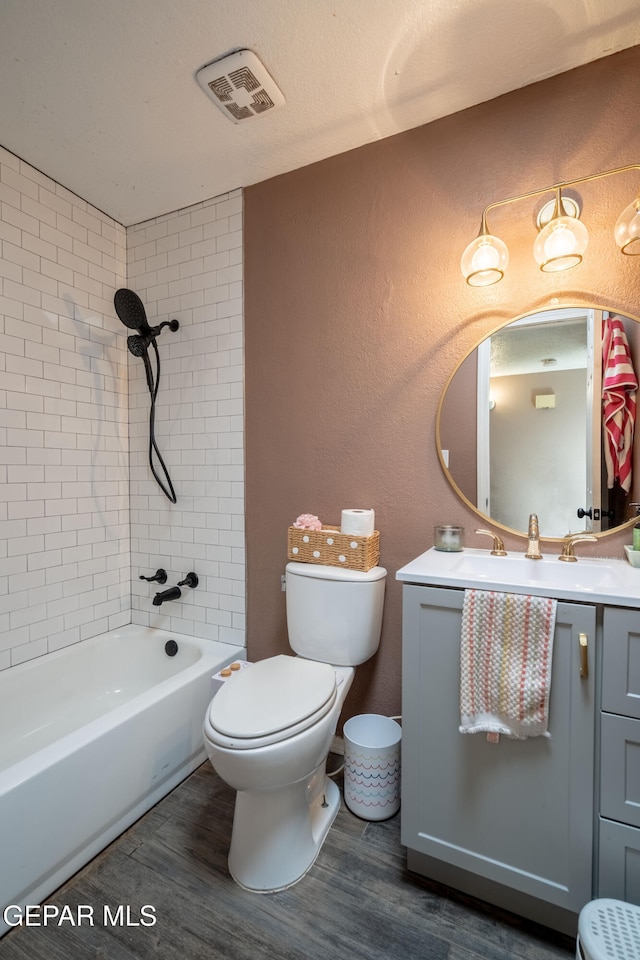 full bathroom with tiled shower / bath, toilet, vanity, and hardwood / wood-style flooring