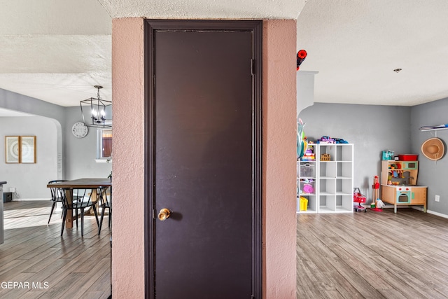 rec room featuring a textured ceiling, a chandelier, and wood-type flooring