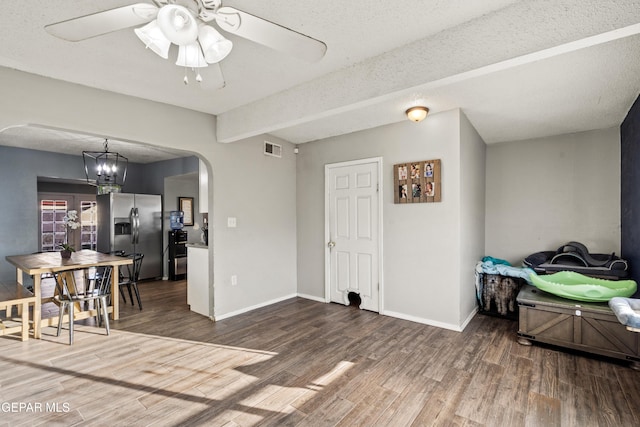 interior space with beamed ceiling, dark hardwood / wood-style flooring, a textured ceiling, and ceiling fan with notable chandelier