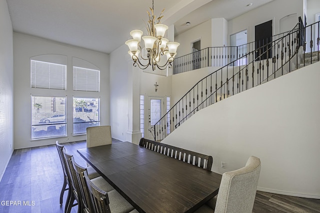 dining room with a towering ceiling, a notable chandelier, and dark hardwood / wood-style floors