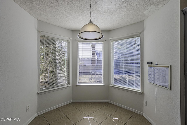 unfurnished dining area featuring a textured ceiling and light tile patterned floors