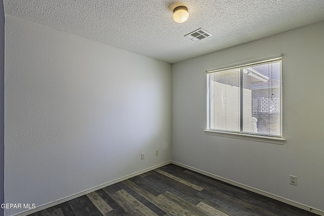 spare room featuring a textured ceiling and dark wood-type flooring