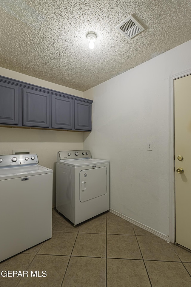 laundry area with a textured ceiling, cabinets, independent washer and dryer, and light tile patterned floors