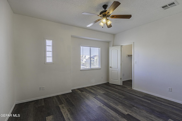 unfurnished room featuring a textured ceiling, ceiling fan, and dark wood-type flooring