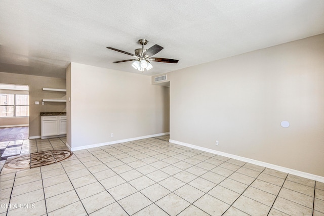 tiled empty room with a textured ceiling and ceiling fan