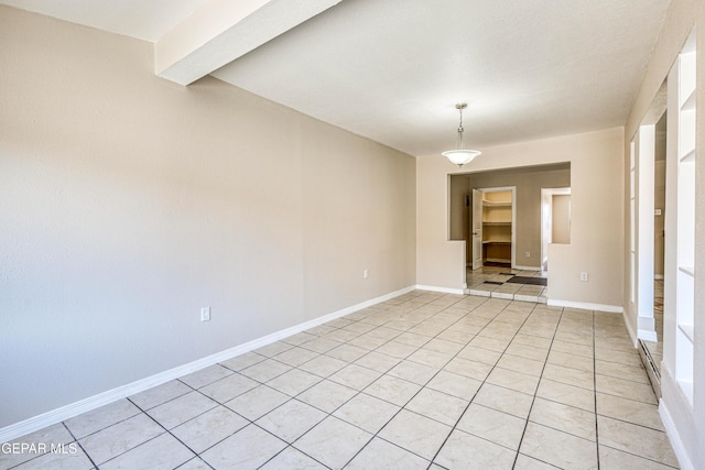 unfurnished room with beamed ceiling and light tile patterned flooring