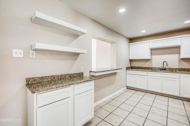 kitchen featuring white cabinets, light tile patterned floors, sink, and dark stone counters