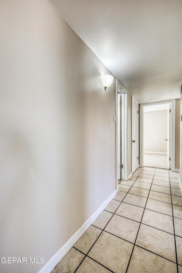 hall featuring light tile patterned floors and a textured ceiling