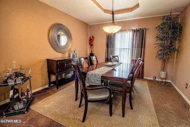 dining space with carpet floors and a tray ceiling