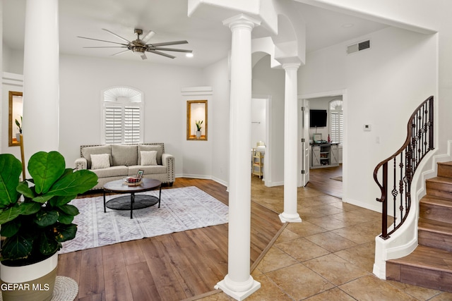 living room featuring decorative columns, light wood-type flooring, and ceiling fan