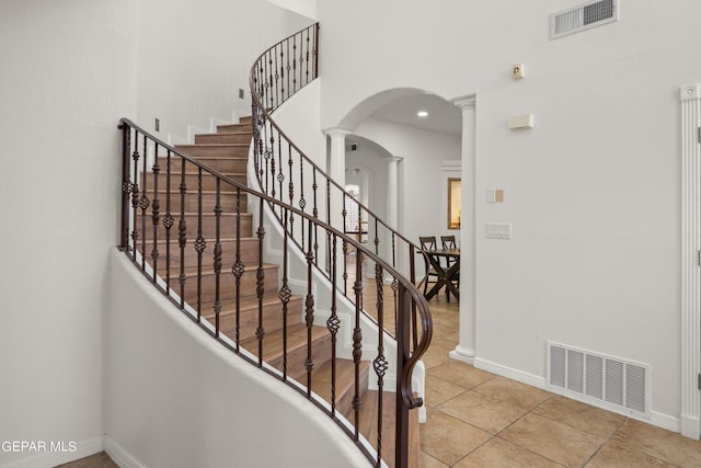 stairs featuring tile patterned floors and ornate columns