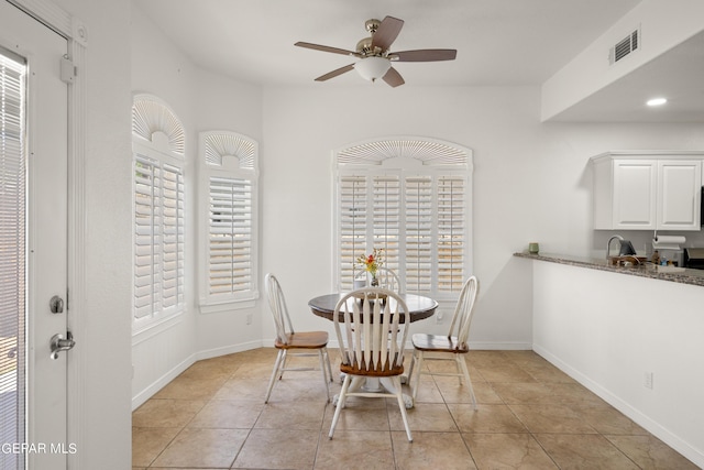 tiled dining space with ceiling fan and plenty of natural light