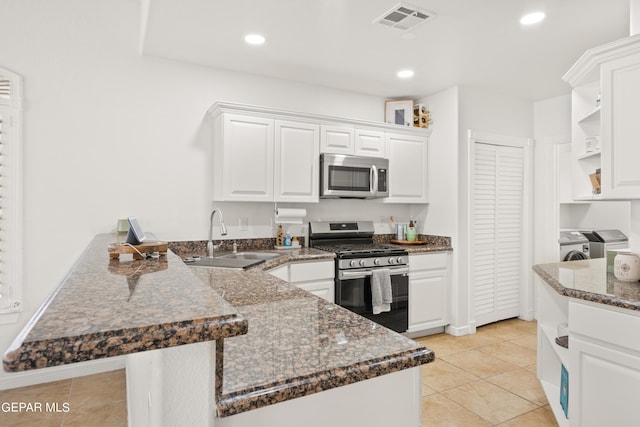 kitchen featuring white cabinetry, appliances with stainless steel finishes, kitchen peninsula, sink, and washer and clothes dryer