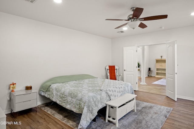 bedroom with ceiling fan, decorative columns, and wood-type flooring