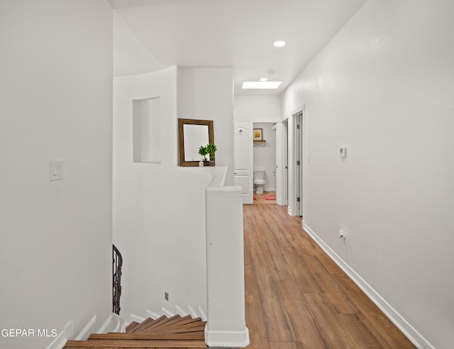 corridor featuring wood-type flooring and a skylight