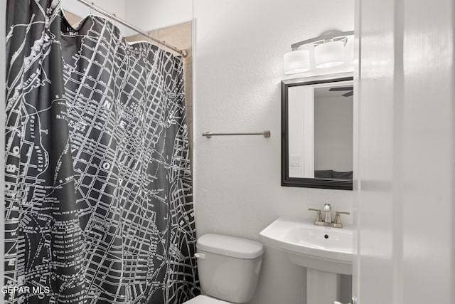 bathroom featuring toilet, a shower with curtain, and sink