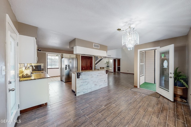 kitchen featuring sink, white cabinetry, stainless steel fridge, a chandelier, and pendant lighting