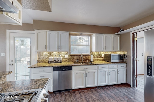 kitchen featuring stainless steel appliances, dark stone counters, dark hardwood / wood-style flooring, sink, and white cabinetry