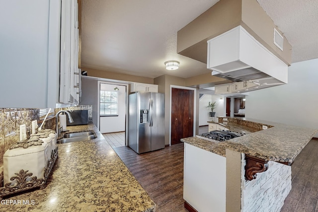 kitchen with appliances with stainless steel finishes, white cabinetry, kitchen peninsula, and sink