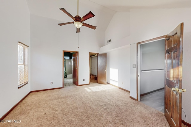 unfurnished bedroom featuring ensuite bath, a closet, high vaulted ceiling, ceiling fan, and light carpet