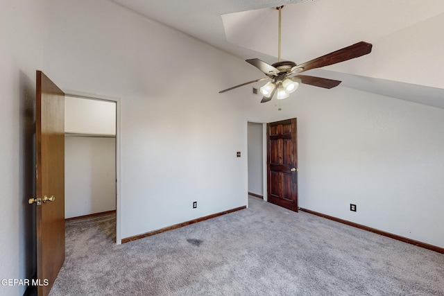 unfurnished bedroom featuring a spacious closet, ceiling fan, a closet, high vaulted ceiling, and light colored carpet