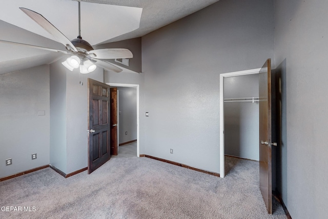 unfurnished bedroom featuring ceiling fan, light carpet, a closet, and lofted ceiling