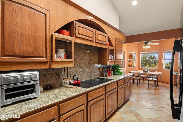 kitchen with light stone counters, lofted ceiling, ceiling fan, backsplash, and black electric cooktop