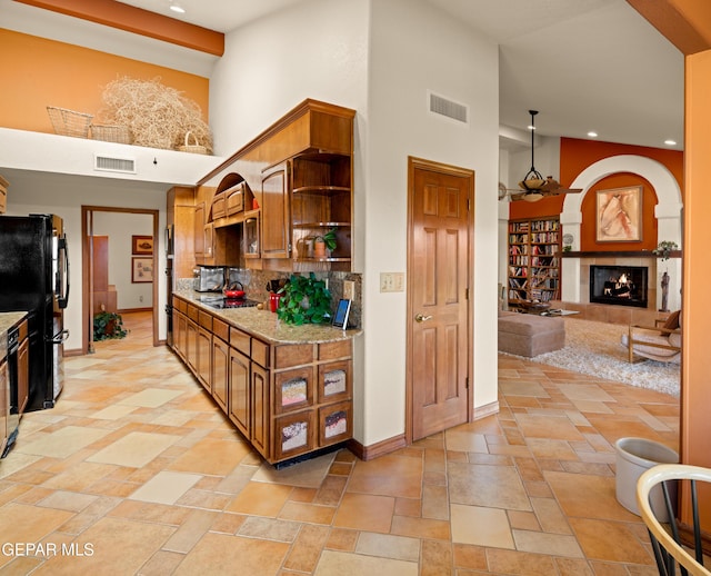 kitchen featuring a fireplace, decorative backsplash, a high ceiling, a chandelier, and black appliances