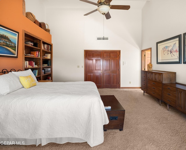 carpeted bedroom featuring a high ceiling, a closet, and ceiling fan