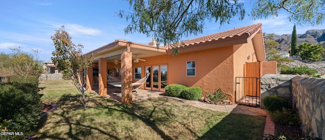 rear view of property featuring ceiling fan, a patio, a yard, and a mountain view