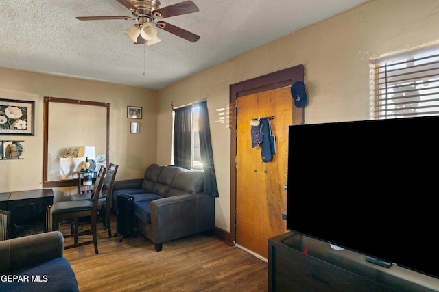 living room featuring ceiling fan, wood-type flooring, and a textured ceiling