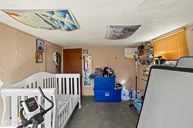 bedroom featuring dark carpet, a textured ceiling, and a nursery area