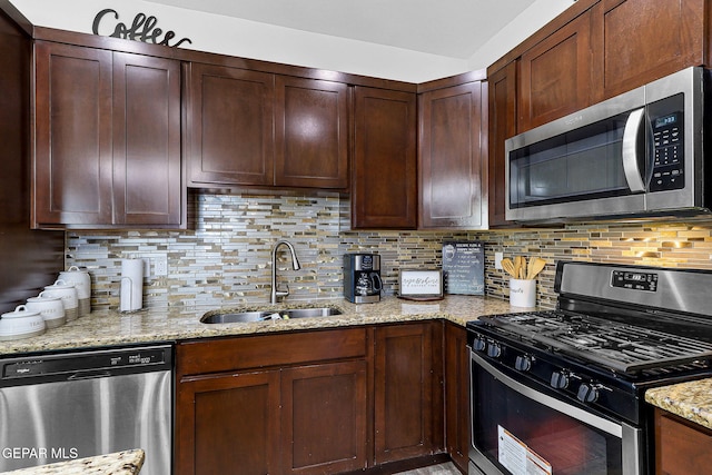 kitchen with sink, stainless steel appliances, light stone counters, and decorative backsplash