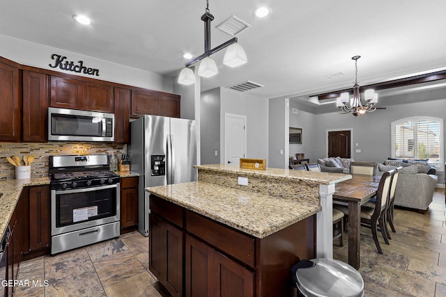 kitchen with a chandelier, a center island, hanging light fixtures, stainless steel appliances, and backsplash