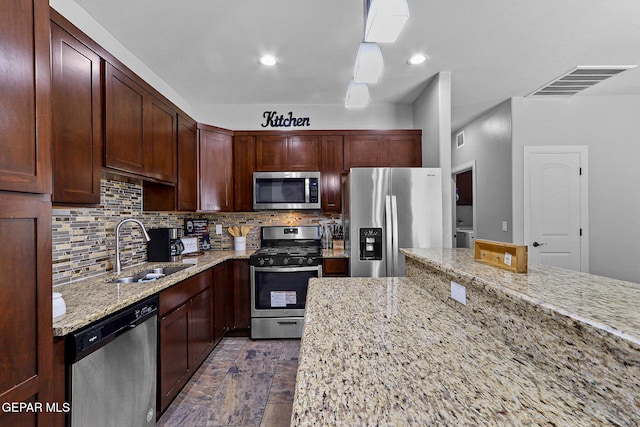 kitchen with stainless steel appliances, decorative backsplash, sink, and light stone counters