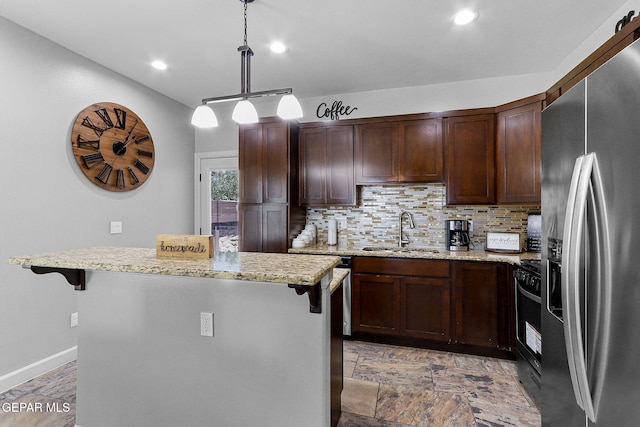 kitchen featuring sink, stainless steel fridge with ice dispenser, a breakfast bar area, and a kitchen island