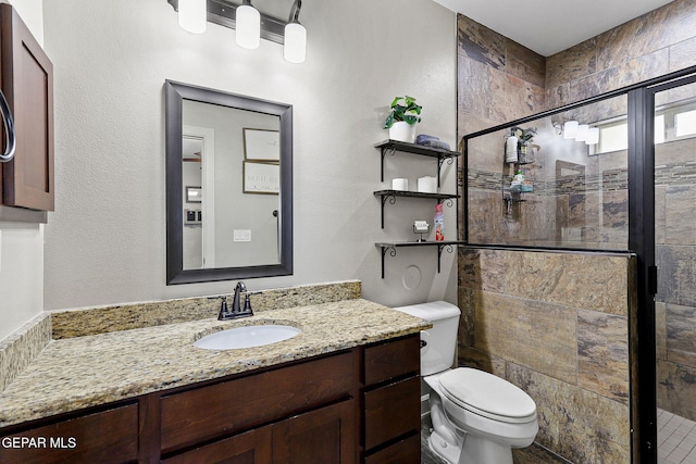 bathroom featuring toilet, a shower with shower door, and vanity