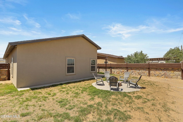 rear view of property featuring an outdoor fire pit, a patio, and a lawn