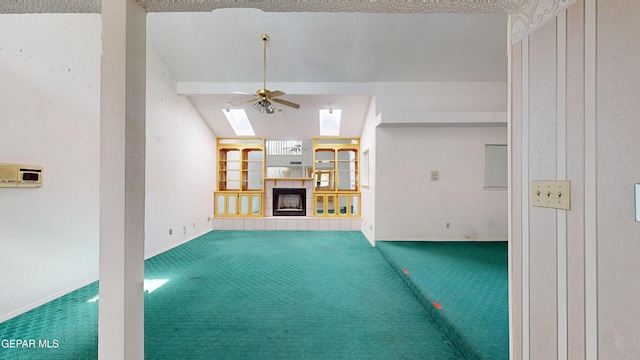 unfurnished living room with a fireplace, ceiling fan, vaulted ceiling with skylight, and carpet