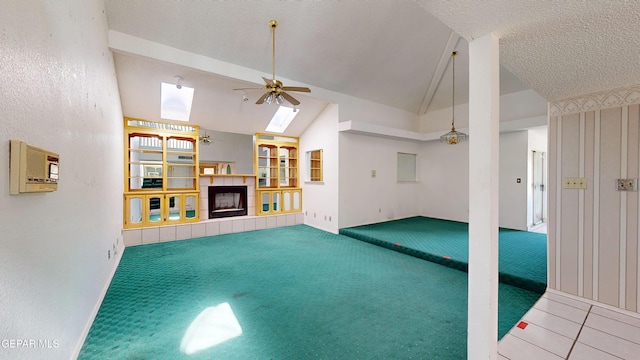 unfurnished living room featuring carpet, a skylight, a textured ceiling, ceiling fan, and high vaulted ceiling