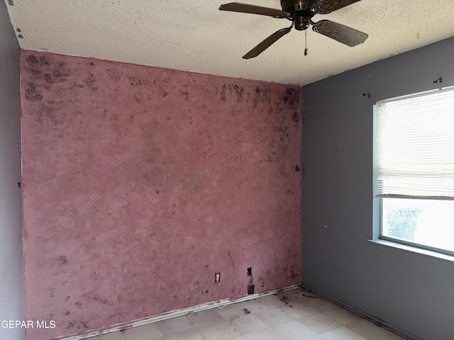 spare room featuring ceiling fan, plenty of natural light, and a textured ceiling