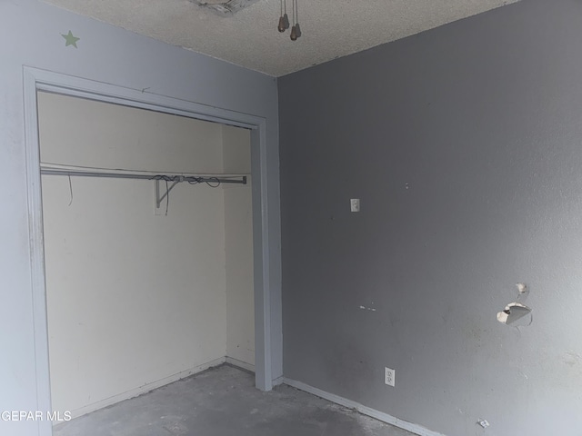 unfurnished bedroom with concrete flooring, a closet, and a textured ceiling