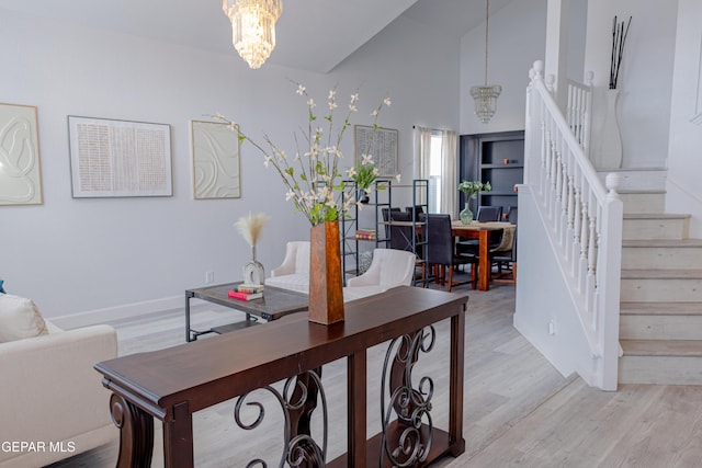 living room with a notable chandelier, light wood-type flooring, and lofted ceiling