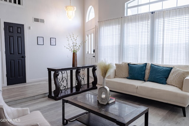 living room featuring hardwood / wood-style floors, an inviting chandelier, and a towering ceiling