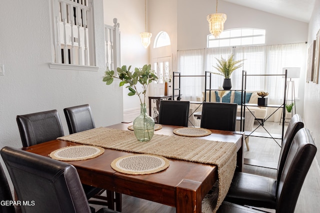 dining room with hardwood / wood-style floors, vaulted ceiling, and a chandelier