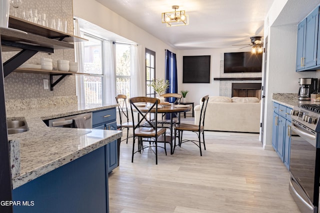 kitchen with stainless steel appliances, blue cabinets, ceiling fan with notable chandelier, and backsplash