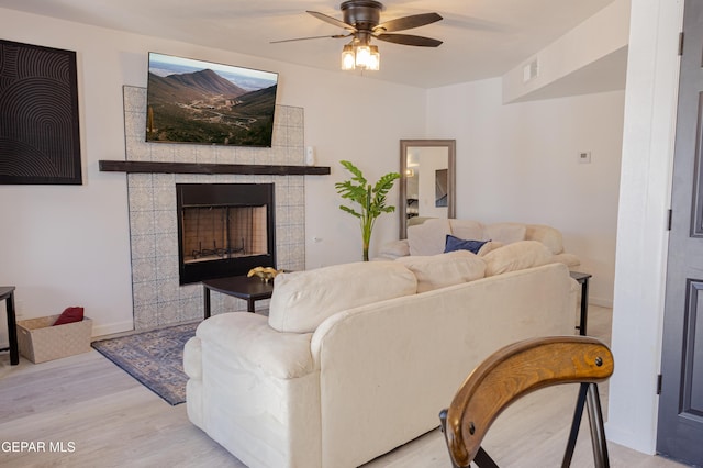 living room with ceiling fan, light hardwood / wood-style floors, and a fireplace