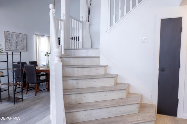 stairway featuring a towering ceiling and hardwood / wood-style flooring