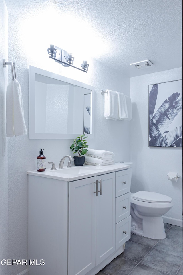 bathroom featuring a textured ceiling, tile patterned flooring, vanity, and toilet