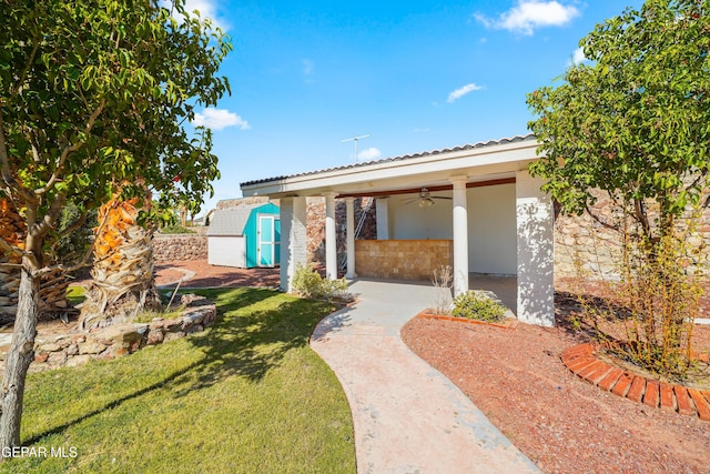 view of front of property featuring ceiling fan, a shed, and a front lawn